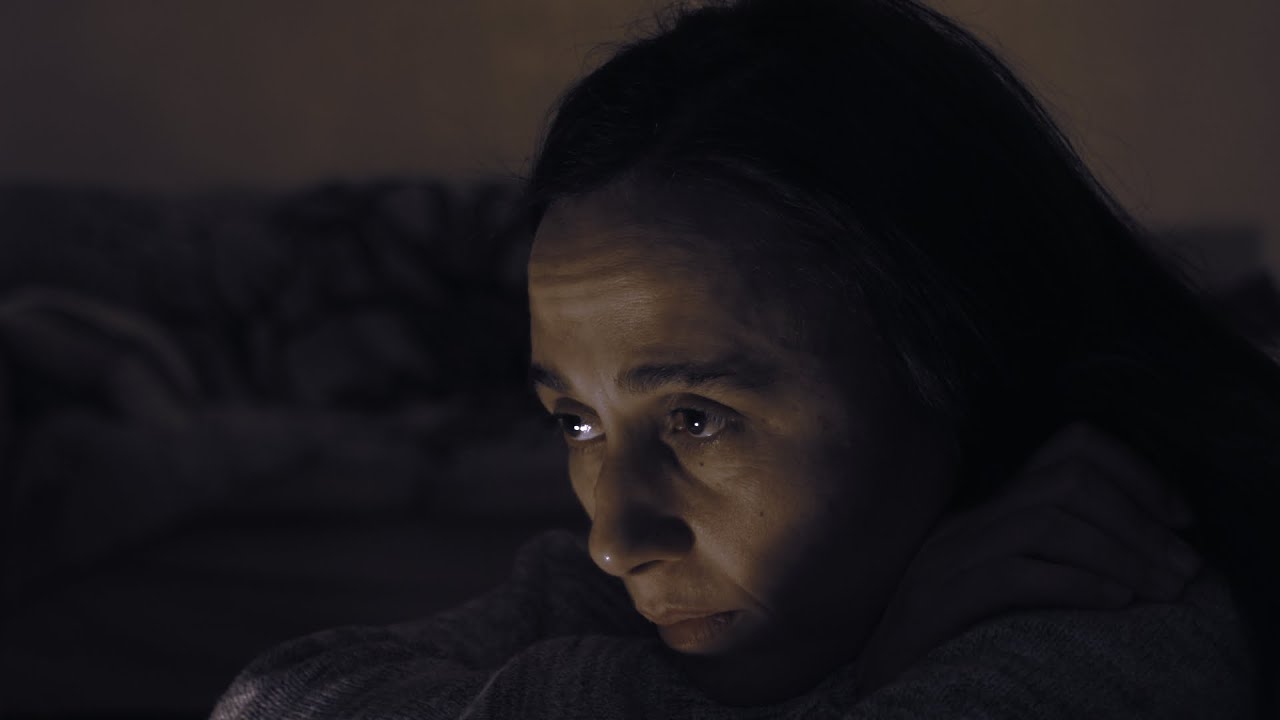 Frame from Birifrangenza: a woman in low light.